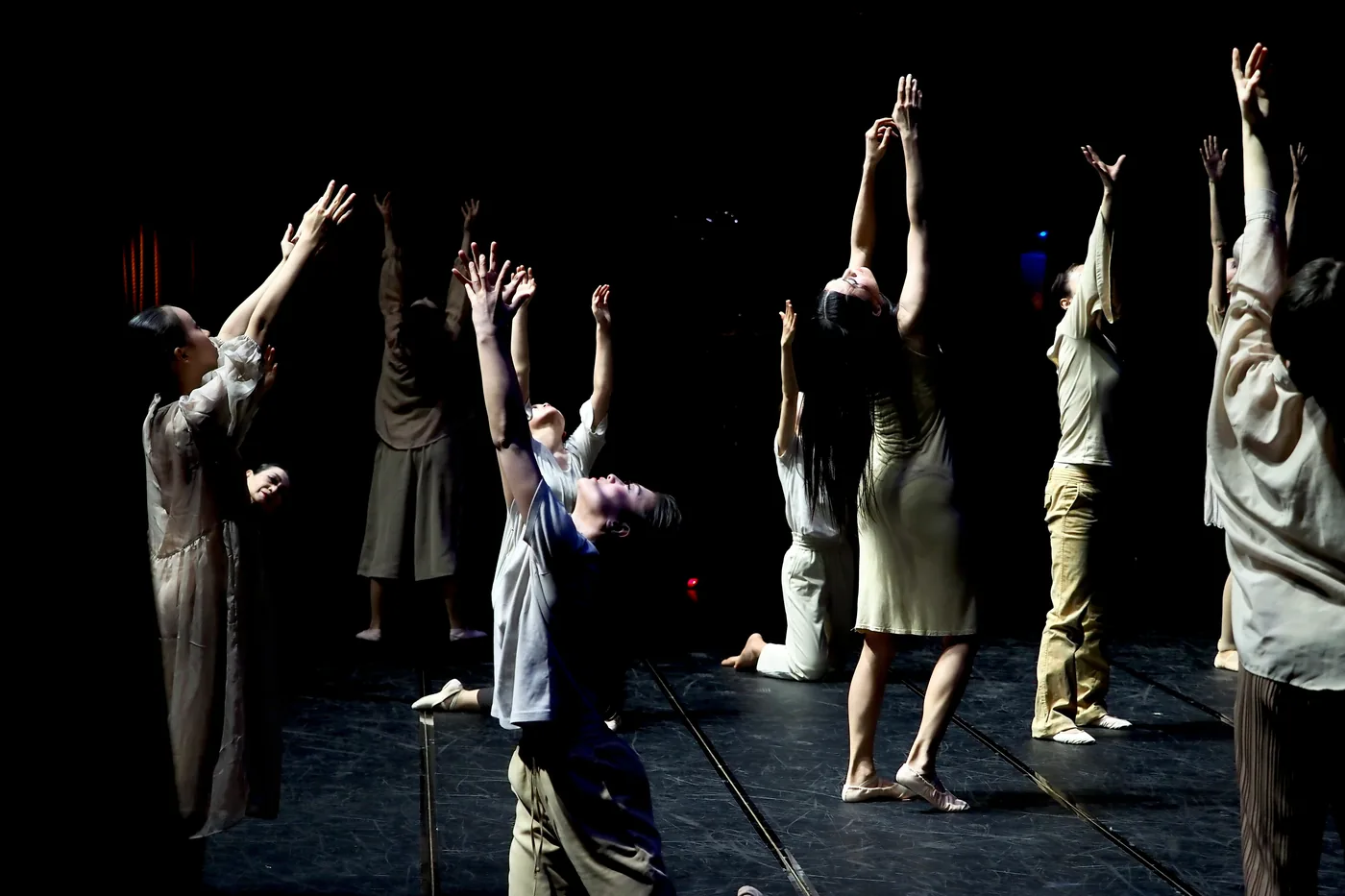 Ensemble gathered on a dark theatre stage.