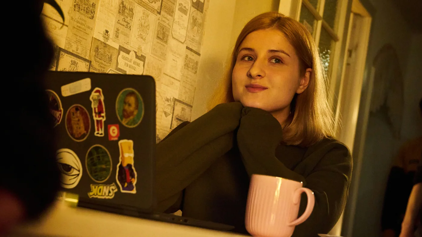 Person seated beside a laptop and mug.