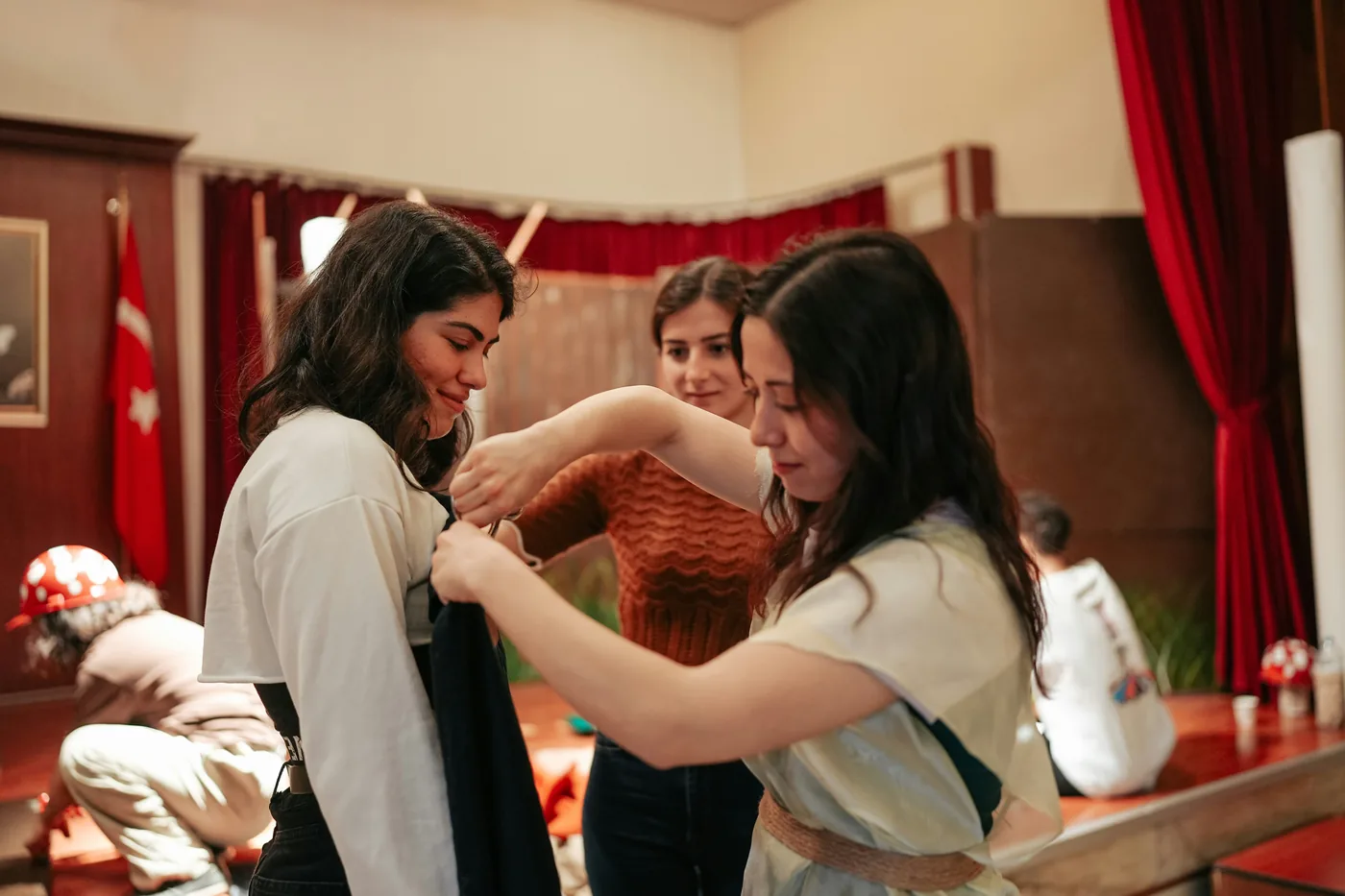 Costume work in a red-curtained rehearsal room.