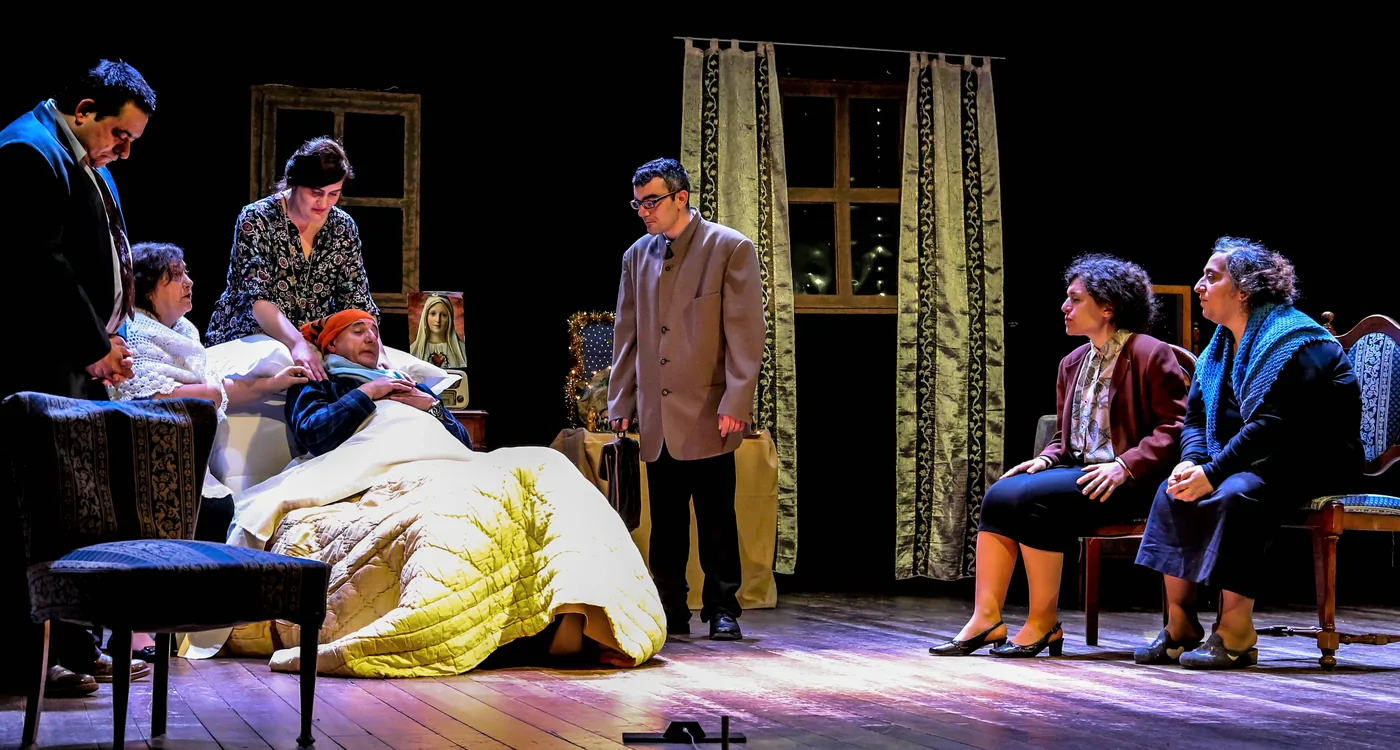 Performers stage a scene around a person lying in bed.