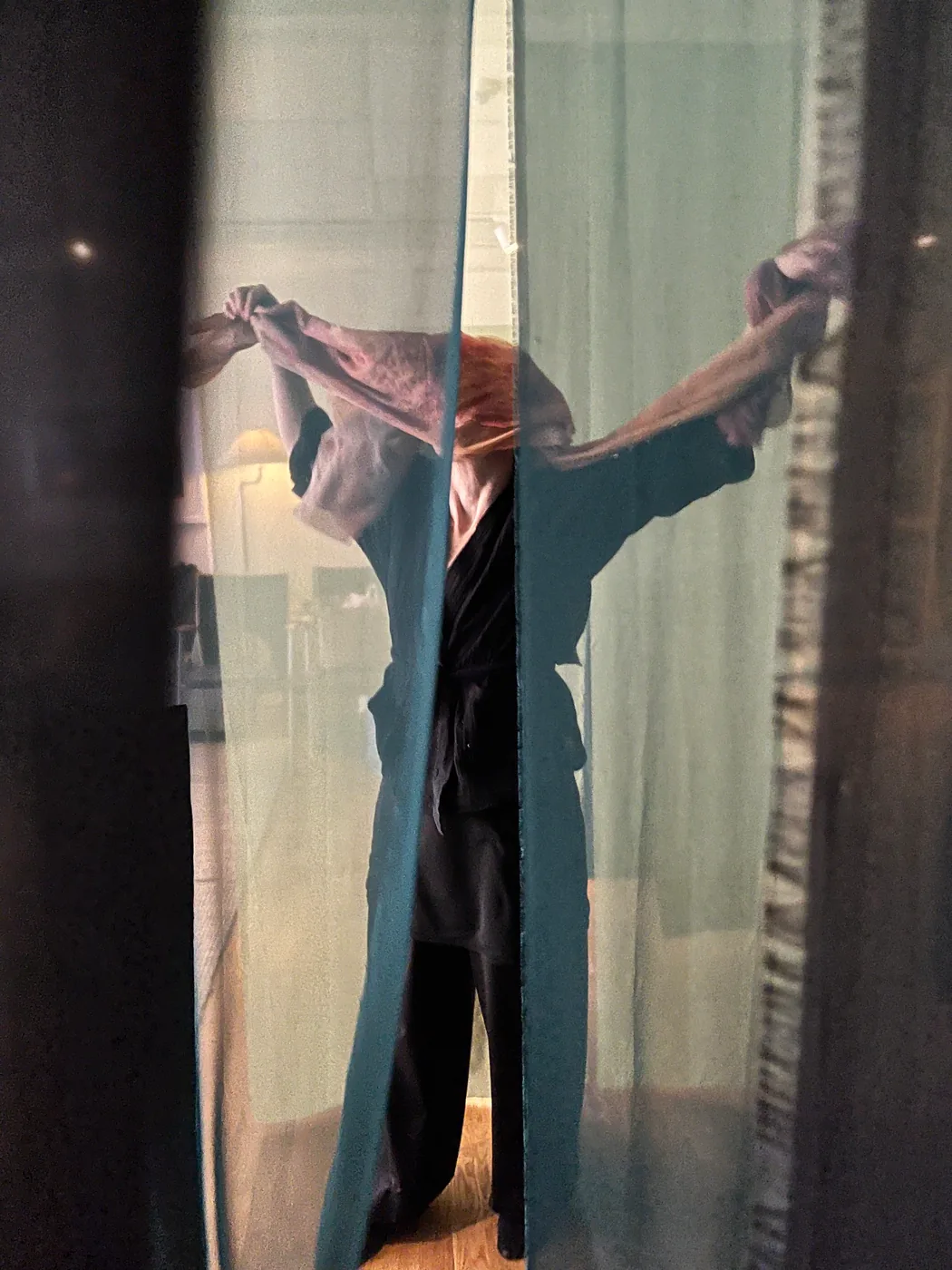 A performer pulls apart a pair of stage curtains.